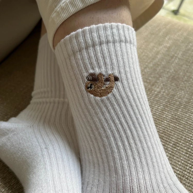 A pair of white crew socks, ribbed, with an animal motif