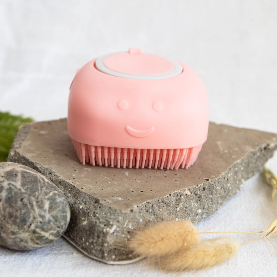 Pink silicone scrubber on a stone surface with a white background