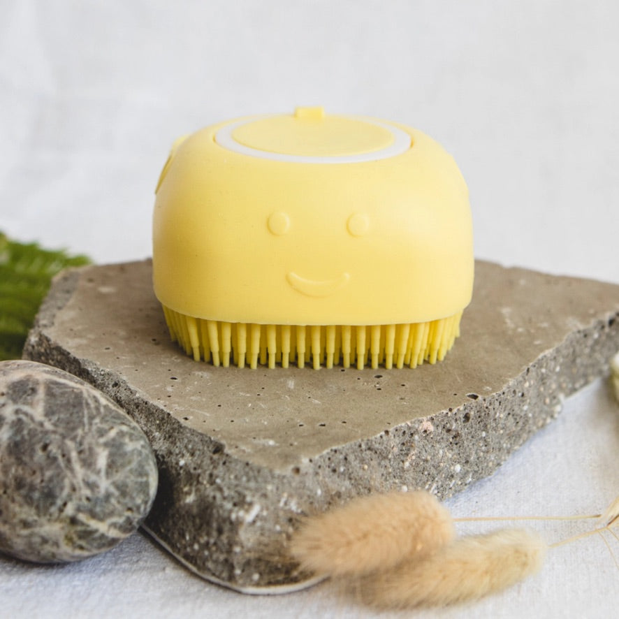 Yellow shampoo brush with a smiley face on a stone surface