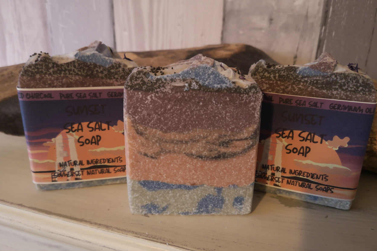 Three bars of sea salt soap with packaging on a wooden surface.
