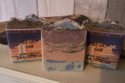 Three bars of sea salt soap with packaging on a wooden surface.