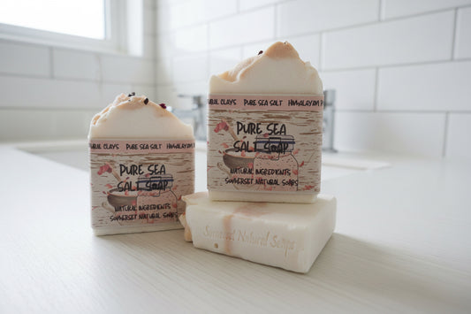 Two bars of Pure Sea Salt Soap on a wooden surface with a blurred background.