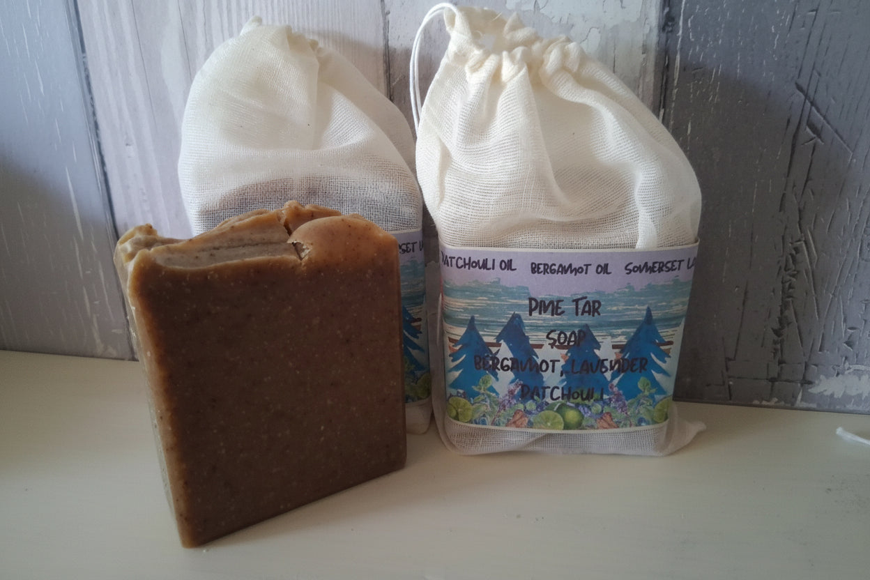 Brown bar of soap with two white drawstring bags on a wooden surface